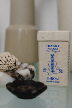 Kadzidełka sznurkowe Chakra Incense na marmurowej podstawce, obok prostokątne opakowanie na kadzidła z papieru czerpanego na szklanym stole