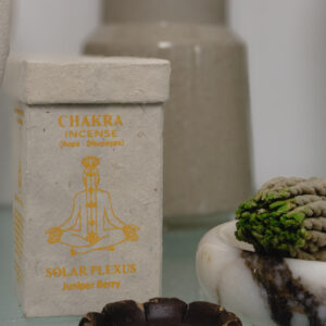 Kadzidełka sznurkowe Chakra Incense na marmurowej podstawce, obok prostokątne opakowanie na kadzidła z papieru czerpanego na szklanym stole