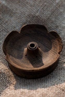 Drewniana podstawka pod kadzidła w kształcie kwiatu lotosu leżąca na lnianym obrusie