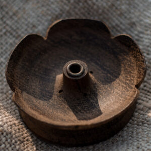 Drewniana podstawka pod kadzidła w kształcie kwiatu lotosu leżąca na lnianym obrusie