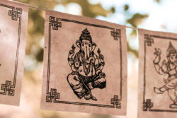 Girlanda z papieru czerpanego lokta z wizerunkiem Ganeshy zawieszona wśród drzew