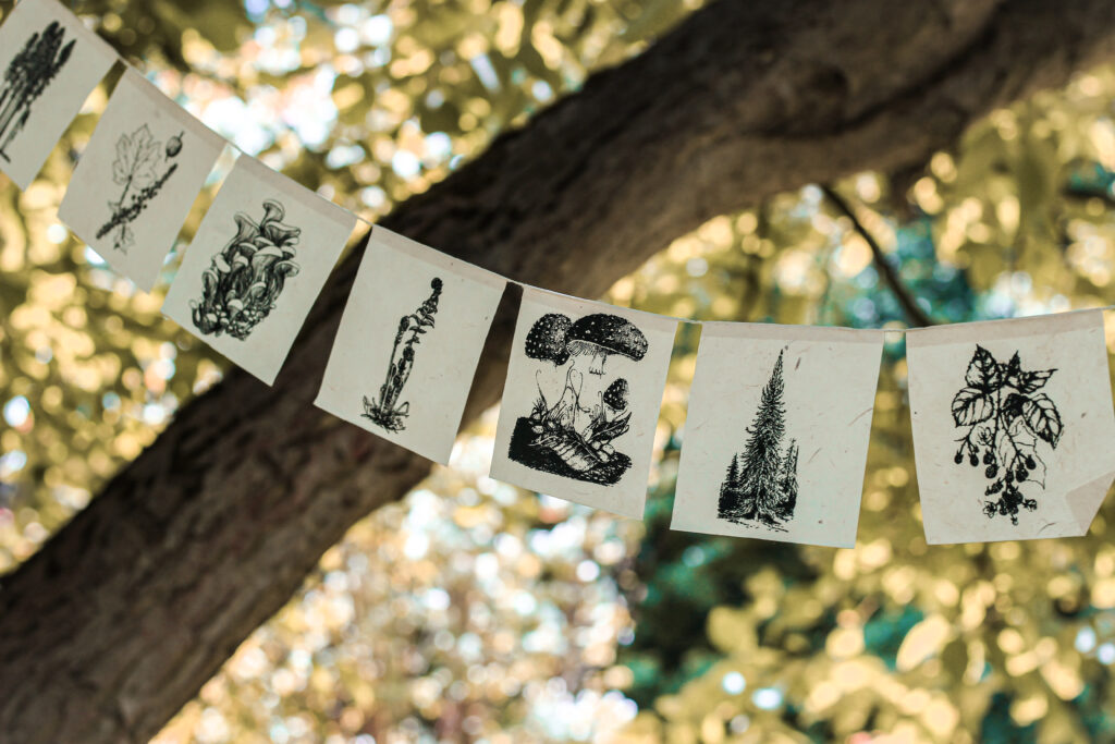 Ozdobna girlanda z flagami z motywami leśnymi - drzewa, grzyby, rośliny wisząca wśród drzew