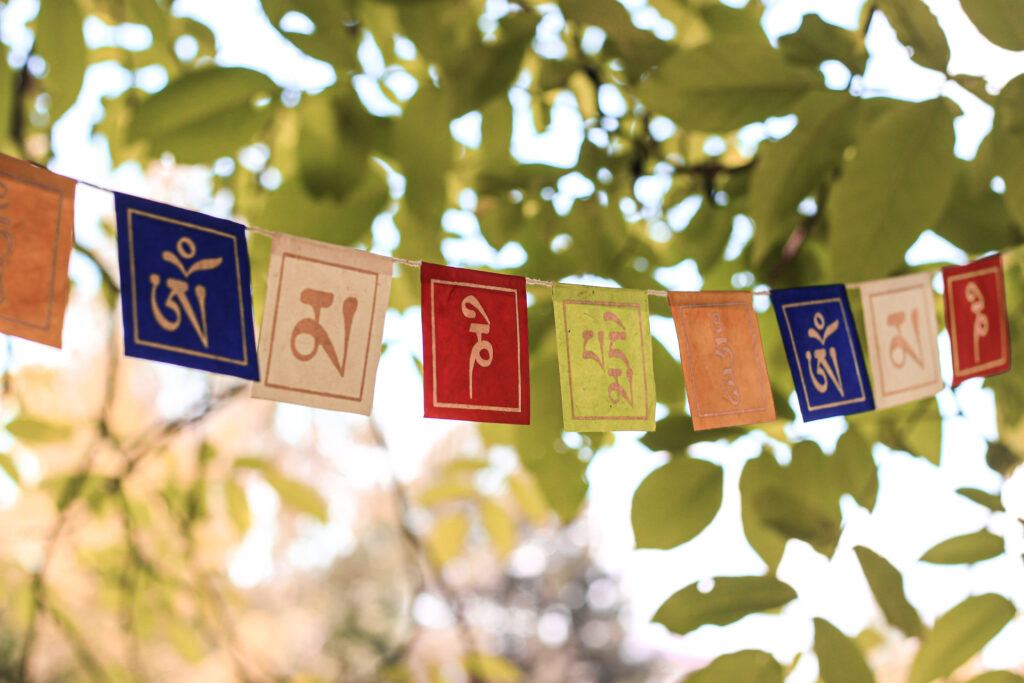 Kolorowa girlanda buddyjska z mantrą Om Mani Padme Hum zawieszona wśród drzew