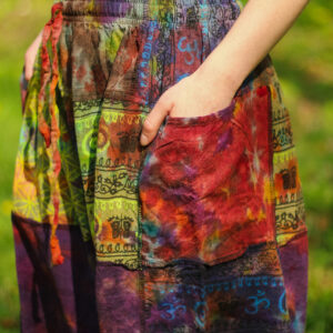 Osoba w tęczowych szarawarach patchwork z rękami w kieszeniach