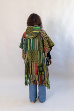 Kobieta z zielonym patchworym ponczo z kapturem na białym tle