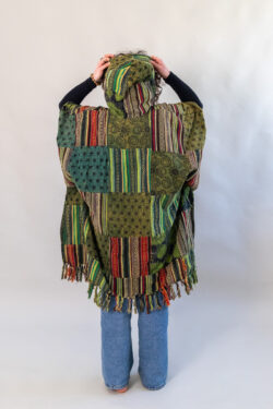 Kobieta z zielonym patchworym ponczo z kapturem na białym tle