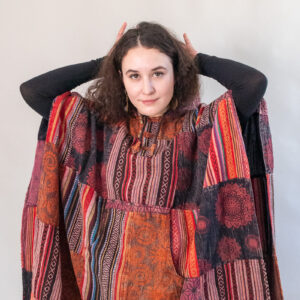 Kobieta w czerwonym patchworkowym ponczo na białym tle