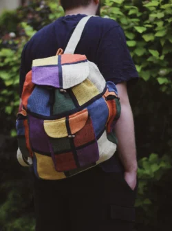 Osoba z kolorowym plecakiem na zielonym tle