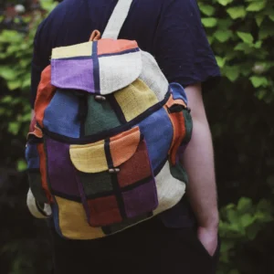 Osoba z kolorowym plecakiem na zielonym tle