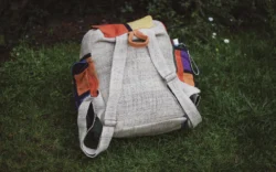 Patchworkowy plecak z konopi z beżowym tyłem i regulowanymi ramionami leżący na trawie