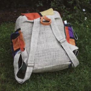 Patchworkowy plecak z konopi z beżowym tyłem i regulowanymi ramionami leżący na trawie
