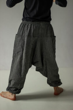 Mężczyzna w czarno-białych szarawarach w paski na białym tle