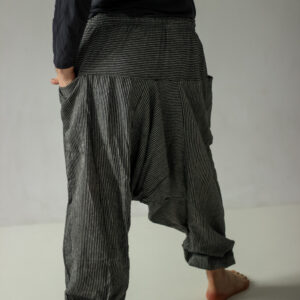 Mężczyzna w czarno-białych szarawarach w paski na białym tle