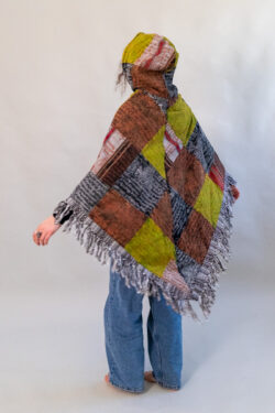 Kobieta w patchworkowym ponczo z kapturem i jeansach na białym tle