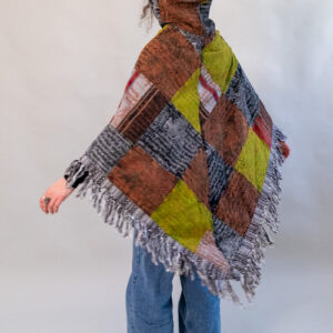 Kobieta w patchworkowym ponczo z kapturem i jeansach na białym tle