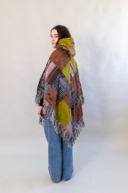 Kobieta w patchworkowym ponczo i jeansach na białym tle