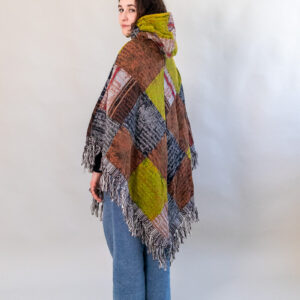 Kobieta w patchworkowym ponczo i jeansach na białym tle