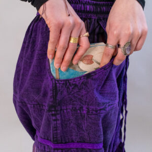 Osoba wkładająca notes do kieszeni fioletowych spodni