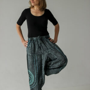 Kobieta w czarnej bluzce i niebieskich szarawarach z symbolem OM