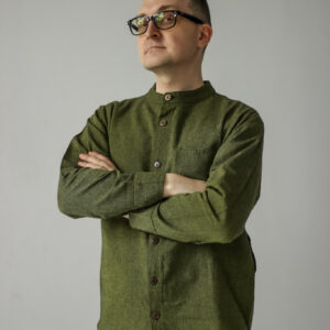 Mężczyzna w okularach i zielonej koszuli zapinanej na drewniane guziki