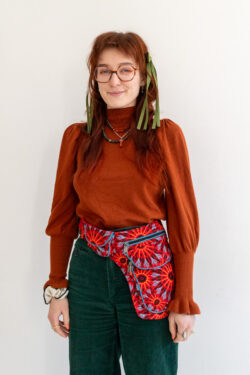 Kobieta w kolorowych ubraniach i czerwonej nerce na pas