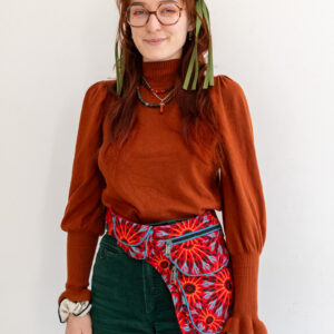 Kobieta w kolorowych ubraniach i czerwonej nerce na pas