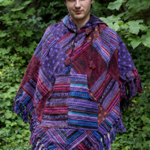 Mężczyzna w trójkątnym, patchworkowym ponczo w fioletowym kolorze na tle zieleni