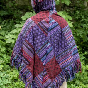 Osoba w trójkątnym, patchworkowym ponczo w fioletowym kolorze na tle zieleni