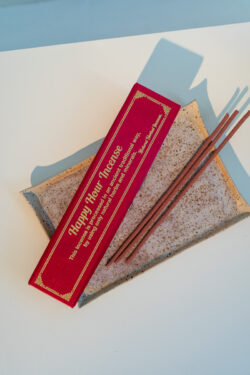 Nepalskie grube kadzidła Happy Hour w ozdobnym czerwonym pudełku, położone na tacy