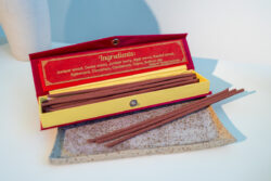 Nepalskie grube kadzidła Happy Hour w ozdobnym czerwonym pudełku, położone na tacy