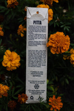 Opakowanie kadzideł Pitta leżące wśród kwiatów.