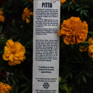 Opakowanie kadzideł Pitta leżące wśród kwiatów.