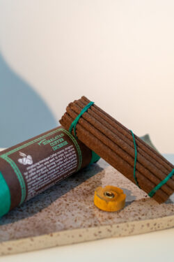 Tybetańskie kadzidła Himalayan Coffee - zestaw kadzideł i podstawka, leżą na glinianej tacy w kropki oparte o tubę z papieru czerpanego.