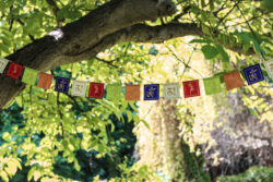 Girlanda z papieru czerpanego z symbolem mantry Om Mani Padme Hum rozwieszona wśród drzew.