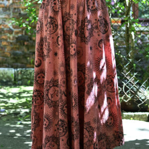 Kobieta w blond włosach i czarnym szydełkowym topie w łososiowej maxi spódnicy w astro wzory na tle zieleni