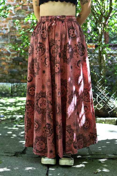 Spódnica astro Kobieta w blond włosach i czarnym szydełkowym topie w łososiowej maxi spódnicy w astro wzory na tle zieleni