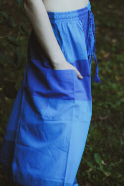 Osoba ubrana w niebieskie szarawary trzyma rękę w kieszeni