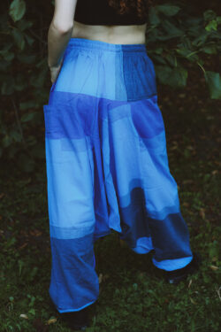 Kobieta stoi tyłem ubrana w czarny top i niebieskie szarawary w geometryczne wzory