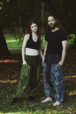 Kobieta i mężczyzna w czarnych bluzkach i szarawarach stoją w parku na tle zieleni