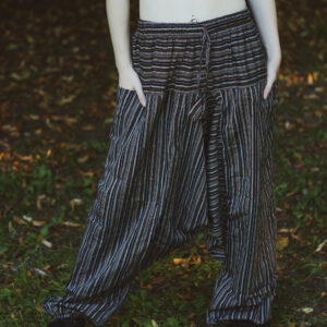 Kobieta w długich rudych włosach w czarnym topie i szarawarach w paski w czarno-biało-brązowe paski