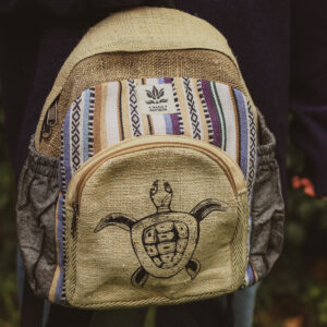 Kobieta w sweterku w paski trzyma mini plecak z nadrukiem żółwia