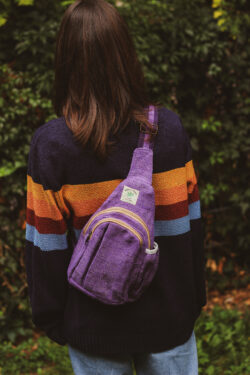 Kobieta w sweterku w paski ma stoi tyłem z plecakiem na jedno ramię Himalayan Hemp w kolorze fioletowym