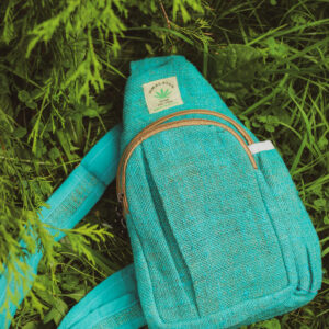 Trójkątny plecak Himalayan Hemp w kolorze turkusowym leży wśród zieleni
