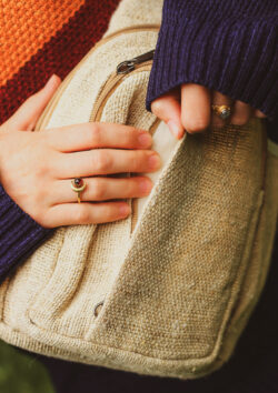 Kobieta z pierścionkami na dłoni otwiera beżowy plecak Himalayan Hemp