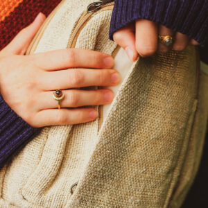 Kobieta z pierścionkami na dłoni otwiera beżowy plecak Himalayan Hemp