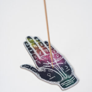 Kolorowa podstawka na kadzidło w kształcie ręki ze znakami zodiaku i astralnymi wzorami, z włożonym kadzidłem, na białym tle