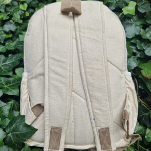 Tylna beżowa część plecaka z kieszeniami po bokach leżącego na bluszczu