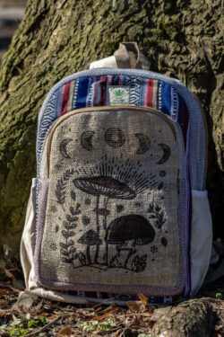 Beżowo niebiesko czerwony plecak z illustracją brązowych grzybów i roślin wykonany z beżowej konopii i kolorowego materiału gheri na tle drzewa