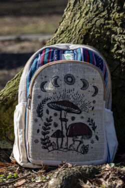Beżowo niebiesko czerwony plecak z illustracją brązowych grzybów i roślin wykonany z beżowej konopii i kolorowego materiału gheri na tle drzewa
