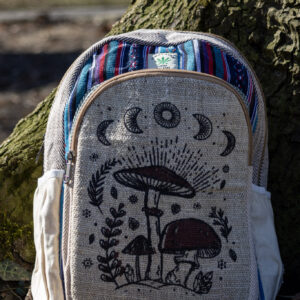 Beżowo niebiesko czerwony plecak z illustracją brązowych grzybów i roślin wykonany z beżowej konopii i kolorowego materiału gheri na tle drzewa